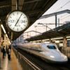時間を指し示すモダンな駅の時計と背後を高速で通過する新幹線